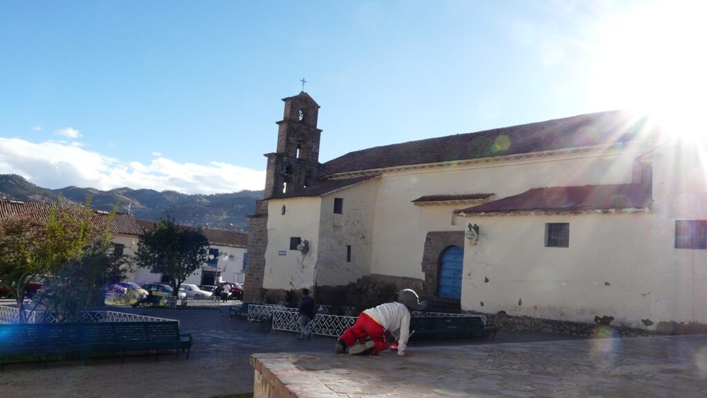 A kid playing at a square in Cusco. You can see an old church in the background.