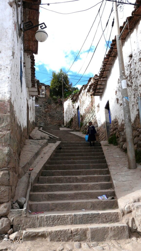 Old cobblestone stairs in a narrow street in San Blas, Cusco. A little girls is standing in the middle of the stairs.
