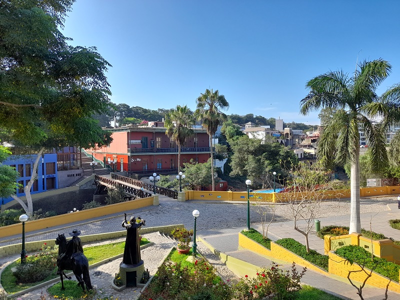 A view of the Bridge of Sighs in Barranco, houses, and sculptures, on a sunny day.