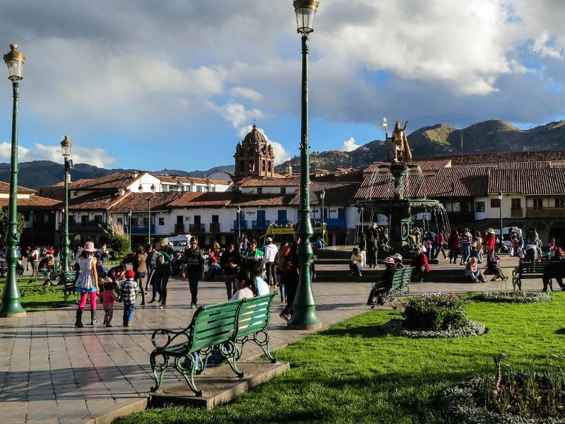 This is the main square in Cusco, a very safe area in the city. People walking around and sitting in benches.