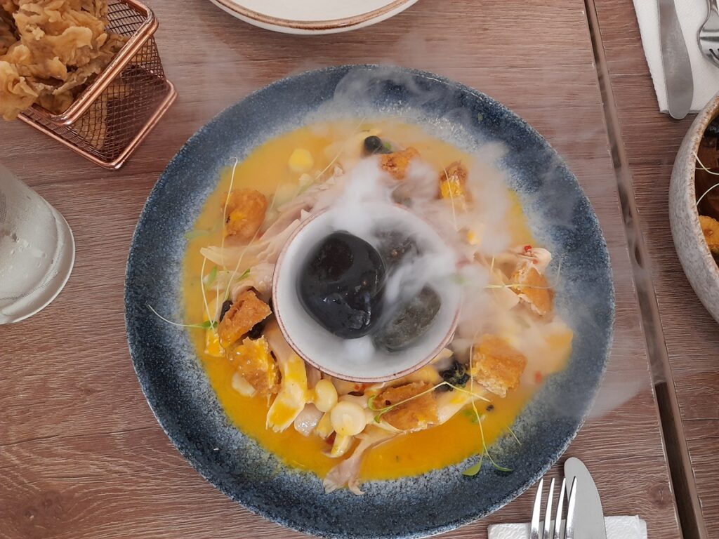 "Exquisite vegetarian cebiche presentation at Asianica restaurant in Lima, with a creative assortment of marinated mushrooms and corn, garnished with a dramatic smoke effect for an enhanced sensory experience, accompanied by crispy fried mushroom chicharron.